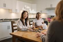 Students gathered around a dining table in a shared residence kitchen.