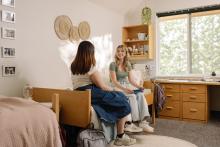 Two students talking in a Robson Hall residence room.