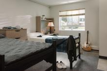 Furnished residence room with a bed, desk, window and guitar in douglas hall