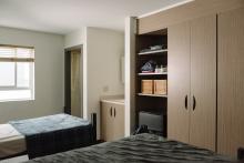 Shared residence room with two beds, wardrobes and built-in shelving.