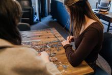 Students assembling a jigsaw puzzle together in The Well.