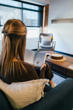 Student reading a book while seated in the lounge at The Well.