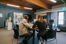 Two students working together at a table in The Well.
