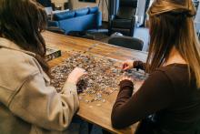 Two students working on a puzzle together at a table in The Well.