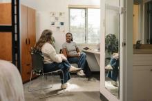 Students having conversation beside a study desk and bed in a shared resident room