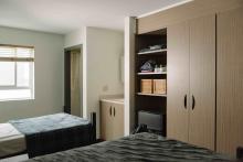 Shared residence room with two beds, wardrobes and built-in shelving.