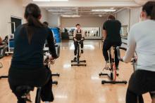 Instructor leading a group cycling class with participants riding stationary bikes.