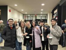 Group of students and guests posing together at an indoor art event.