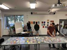 Students arranging colourful paper samples and artworks during a studio activity.
