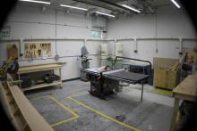 SAMC woodworking shop with a table saw, band saw, workbenches, and wall-mounted hand tools.