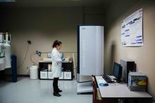 Student in a lab coat working beside scientific equipment in laboratory.