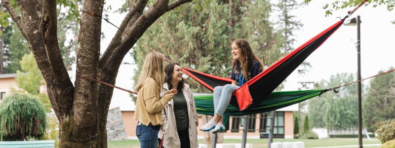 Students on Langnley campus in hammocks talking.