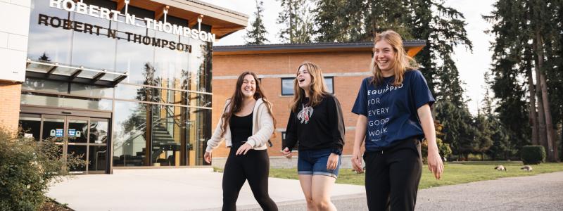 Three students happily walking past Robert N. Thompson