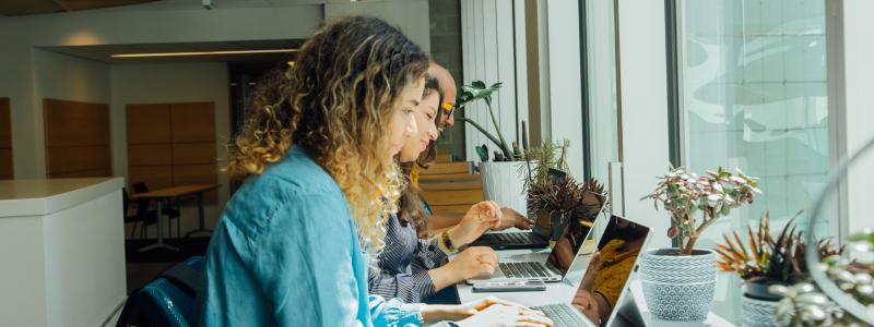 Three students sitting side-by-side studying on their computers