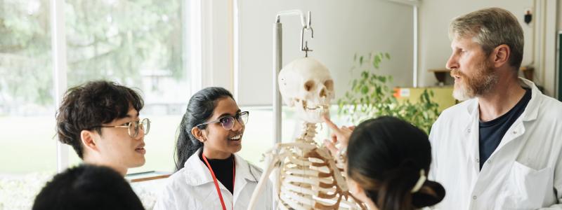 Students in class with professor looking at a skeleton