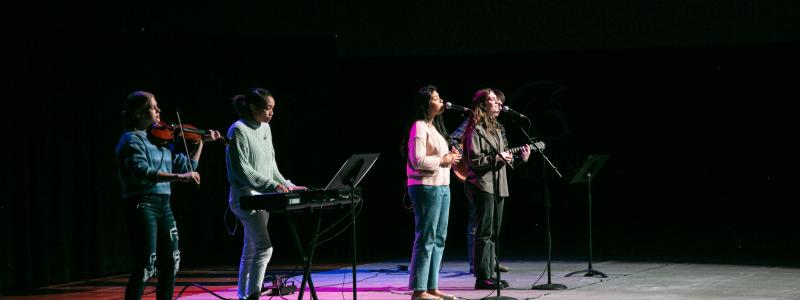 TWU's chapel worship band on stage in the gym. There are instruments and purple lights.