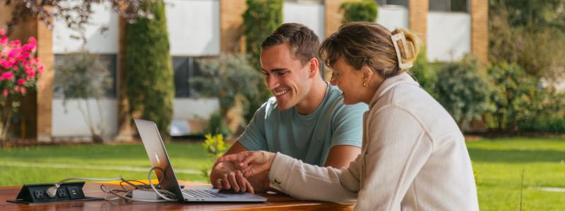 Students looking at laptop outdoors