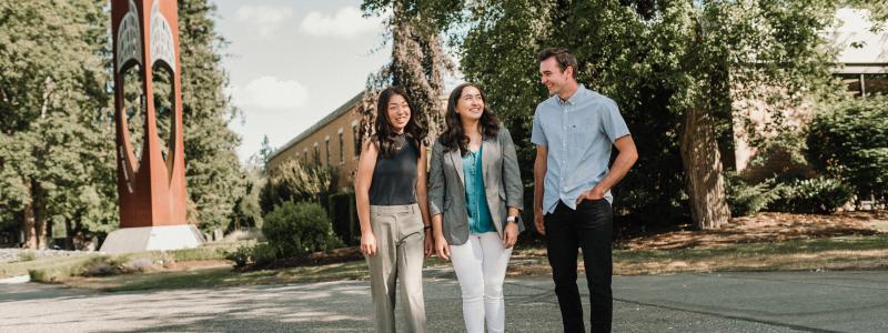 Three happy students standing outside the Bell Tower