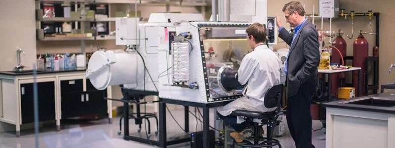 Research lab with student using a machine and professor instructing