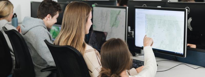 student pointing at screen with map in computer lab