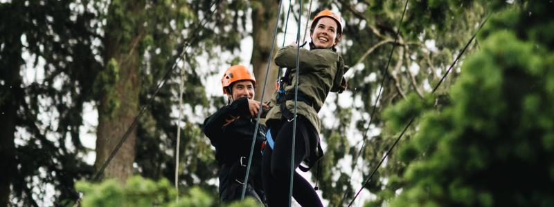 two people on high ropes in trees