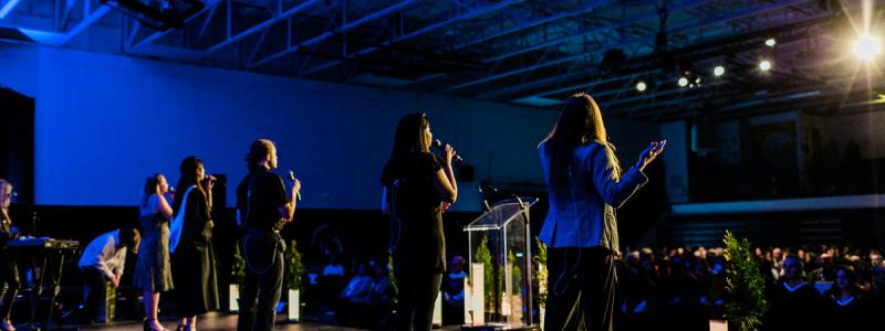 people standing on stage in gym signing
