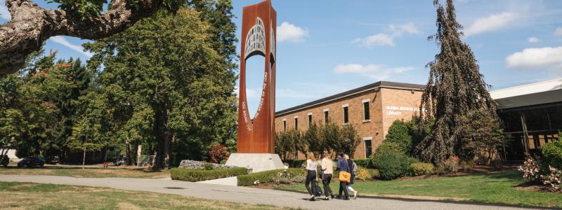 people walking outside in front of bell tower