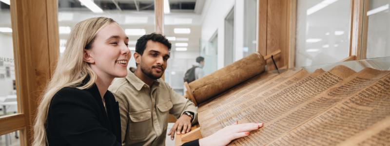 smiling students interacting with Torah scrolls