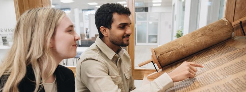 two students engaging with biblical scrolls