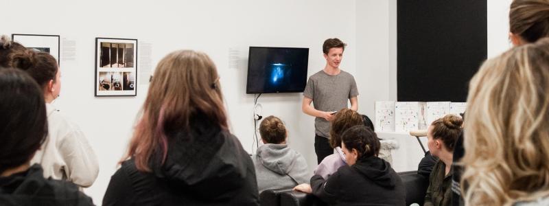student displaying art to audience using a display