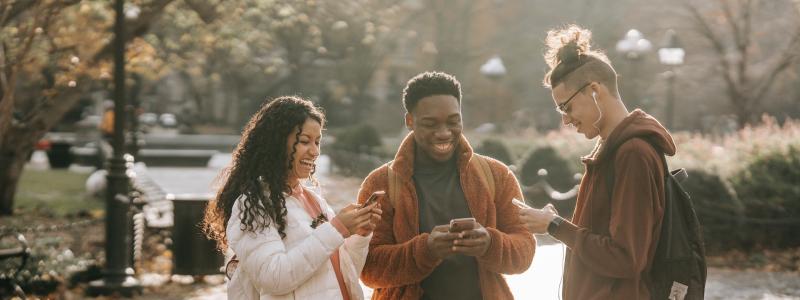 people looking at their phones outside and smiling