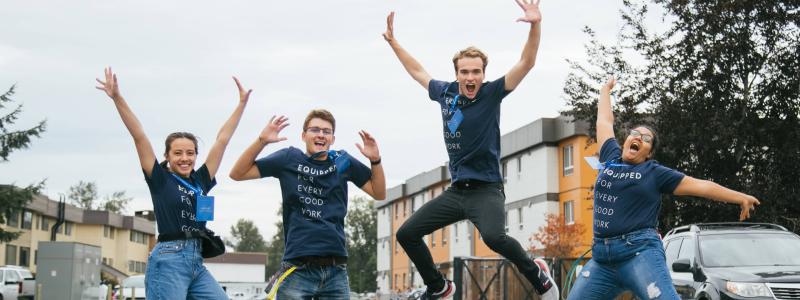 Students jumping with arms up, wearing TWU "Equipped for every good work" shirts.