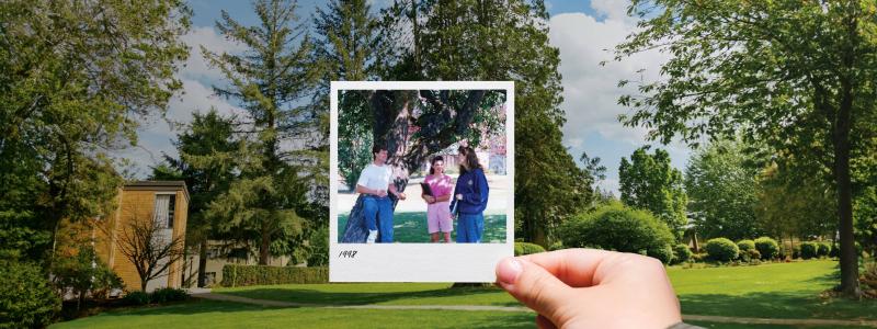 person's hand holding Polariod photo in front of green space