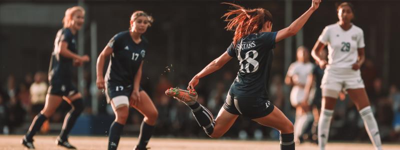 female student athletes playing soccer on field