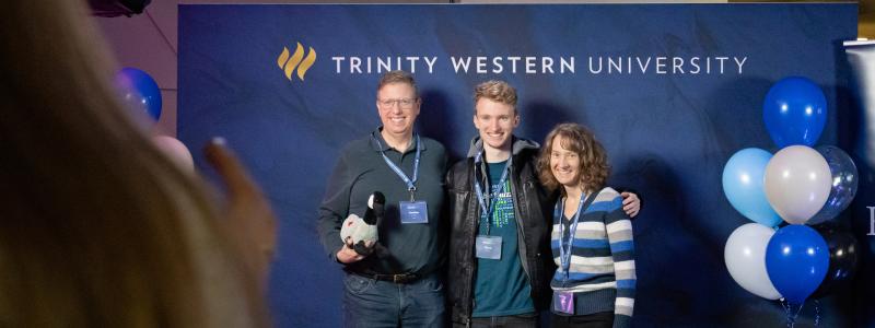 parents standing with student in front of TWU backdrop