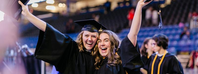two women cheering and smiling at graduation