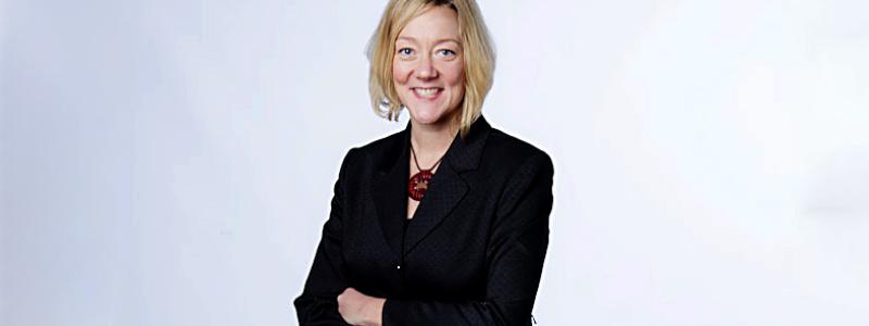 woman standing in front of white background with arms folded