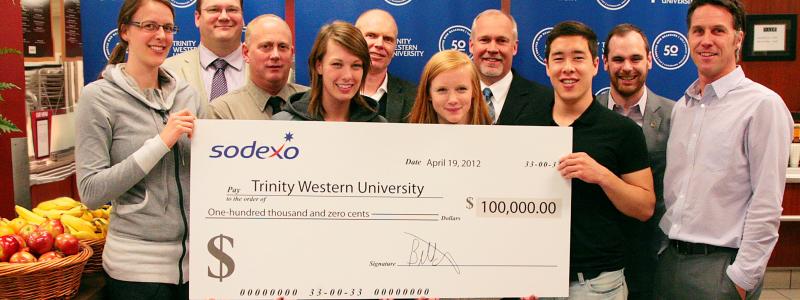 A group of people standing with a cheque.