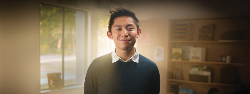 Sean Hui standing in front of classroom with light behind