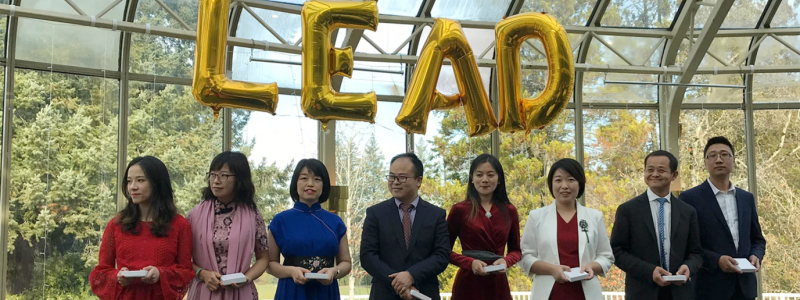 MA lead students standing in a glass building with baloons reading LEAD above them