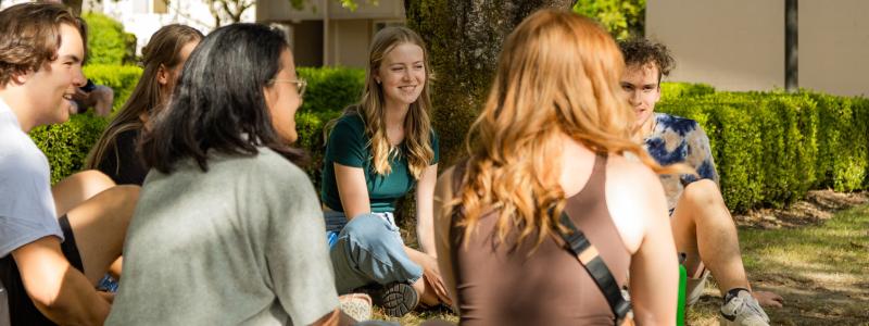 Students sitting on a lawn in a circle.