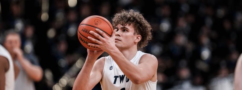 A basketball player in a white "TWU" jersey with number 9 prepares to shoot.