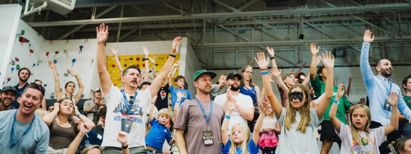Crowd cheering indoors, arms raised, showing excitement at Homecoming 2025.