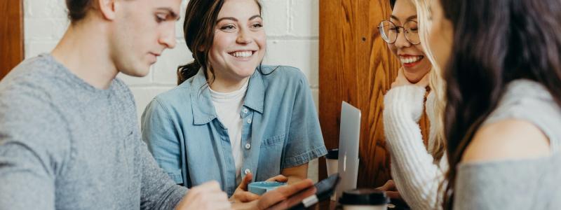 Four people smiling and chatting around a table.