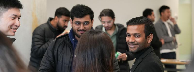 Group of people smiling and chatting in a hallway.