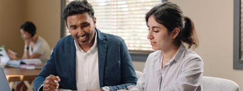Two students studying together at a table with open books.
