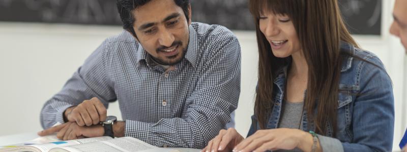 Two people studying at a table with open books.