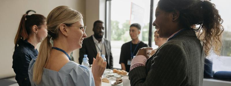 People in business attire chatting and smiling at a networking event.