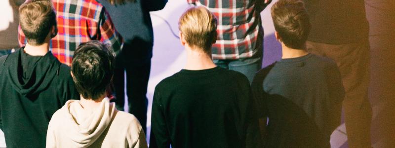 Crowd of people standing in a dimly lit room.