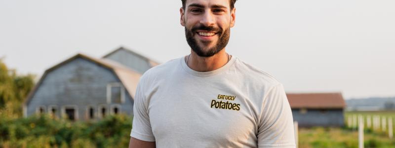 Man smiling in front of a farm with barns.